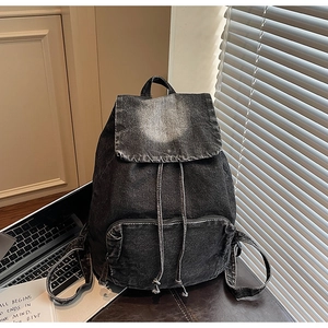 Detail of black washed denim backpack with drawstring flap and front zipper pocket