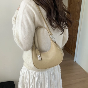 Détail du sac demi-lune en cuir kaki clair avec texture litchi et boucles argentées