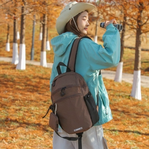Detail of dark brown checkered nylon backpack with small zipper pouch in autumn forest