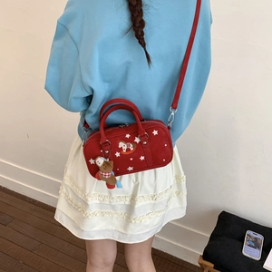 Detail view of red pillow bag with star embroidery and brown teddy bear charm accessory