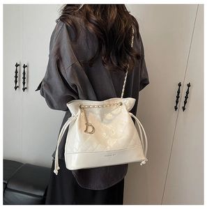 Détail du sac seau matelassé blanc avec bandoulière chaîne dorée et pendentif en métal D