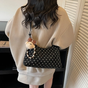 Black polka dot shoulder bag with cute bear charm shown on a model from back view