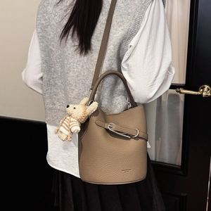 Detail of khaki bucket bag with lychee pattern leather and plush doll charm