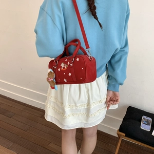 Detail view of red pillow bag with star prints and a plush bear pendant accessory