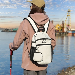 Outdoor back view of a white nylon waterproof backpack featuring a detachable coin purse