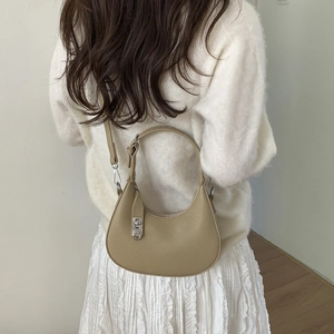 Mannequin portant un sac bandoulière demi-lune beige avec fermoir rotatif en cuir grainé