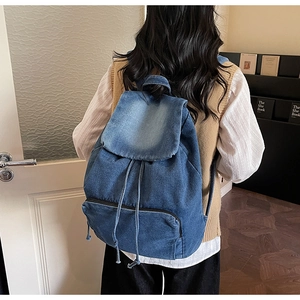 Detail view of denim backpack showing washed fabric texture and drawstring closure system
