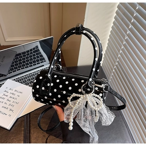 Close-up of small polka dot barrel bag with pearl lace bow charm and glossy finish