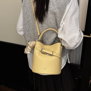 Detail of yellow bucket bag with dog charm on model back view from a side angle
