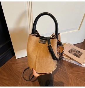 Close-up of retro brown bucket bag with black leather handle and floral bead charm