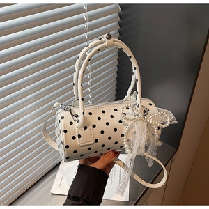 Detailed shot of white polka dot cylinder bag with pearl bow and lace charm