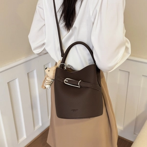Detailed view of brown lychee leather bucket bag with silver buckle and bear charm accessory