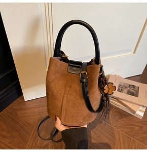 Detail showing vintage suede bucket bag texture with retro beaded clover charm accessory