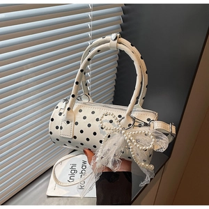 Detailed view of white polka dot cylinder bag with pearl bow and lace accents
