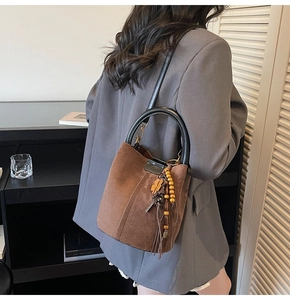 Detail view of brown suede bucket bag featuring beaded charms and leather tassel accents