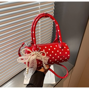 Detail of red cylindrical polka dot handbag with pearl bow and lace charm decoration