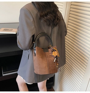 Detail of dark brown matte bucket bag with floral charm and black circular handle