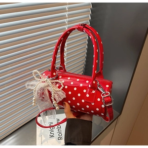 Detail of red polka dot cylinder handbag with decorative pearl lace bow charm