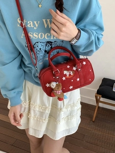 Retro red pillow bag with star prints and horse charm worn by a model in casual style