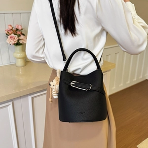 Detailed view of black bucket bag with lychee texture and cute bear pendant accessory