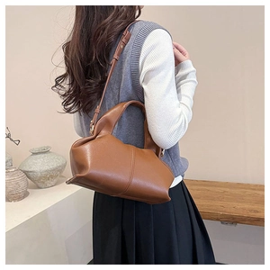 Brown leather cloud bag with vertical stitch detail and adjustable strap on model