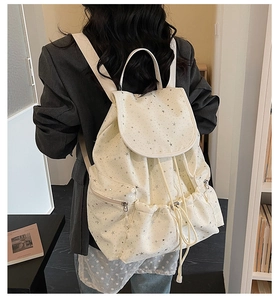 Detail of cream backpack with silver star patterns in a cozy academic library setting
