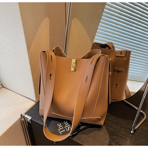 Détail d'un sac seau marron avec motif litchi, fermoir doré et large bandoulière