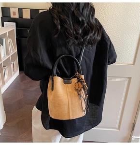 Detail of vintage brown suede bucket bag with wooden bead and leather clover charm