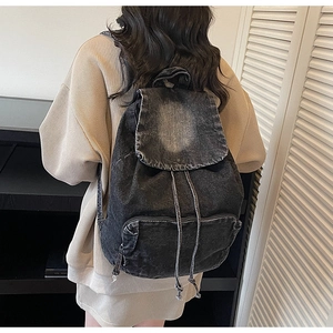 Detailed shot of large capacity washed black denim backpack with drawstring closure and flap
