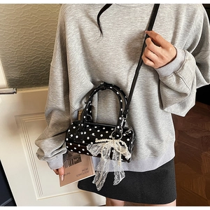Polka dot cylinder bag featuring a white lace bow and elegant pearl charm detail