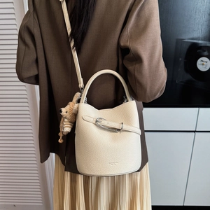Detail view of off-white bucket bag with a cute bear charm on a female model
