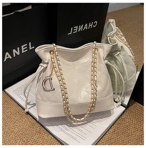 Détail du sac seau matelassé crème avec bandoulière chaîne et pendentif lettre dorée