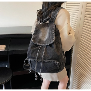 Detail of vintage grey denim backpack with flap drawstring closure and front zipper pocket