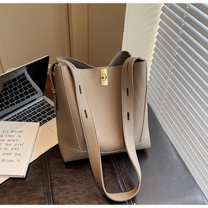 Détail du sac seau en cuir taupe avec fermoir doré sur un bureau moderne et chic