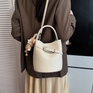 Chic cream-colored leather bucket bag shown from behind with cute dog charm accessory