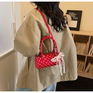 Close-up of red polka dot cylinder bag with lace bow and pearl details in model shot