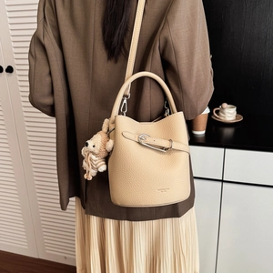 Chic beige bucket bag detail featuring lychee pattern leather and cute bear charm