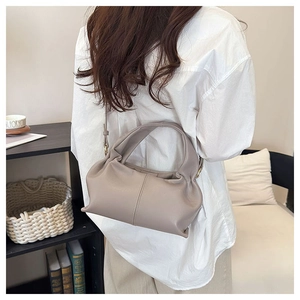 Detail view of a taupe ruched cloud bag showing the soft leather texture and handle