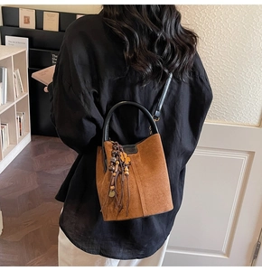 Close-up of brown suede bucket bag featuring bohemian wooden beads and tassel charms