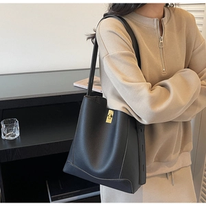 Sac seau chic noir à motif litchi avec boucle dorée présenté en scène de vie