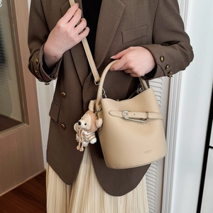 Elegant beige bucket bag in lychee pattern leather styled with a cute plush bear pendant