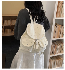 Detailed back view of a white canvas star-patterned backpack in a library setting