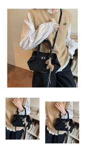 Detalle de bolso bandolera negro con hebilla plateada y colgante de caballo en modelo