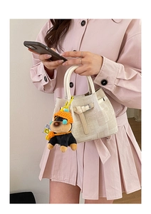 Detail of cream canvas bucket bag with leather strap and cute puppy plush charm