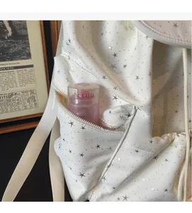 Detail view of a white backpack with silver star patterns showing a side zipper pocket