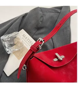 Detail of red leather bucket bag with silver twist lock and adjustable shoulder strap