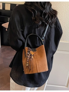 Brown suede bucket bag with vintage charm, featuring ethnic tassels and dual straps
