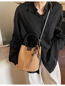 Elegant tan suede bucket bag with round handles and floral charm for women