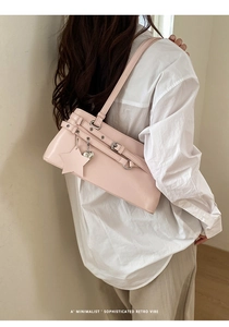 Détail de sac baguette rose minimaliste avec breloques étoile et cœur porté à l'épaule