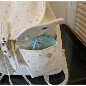 Detail of the magnetic buckle pocket on a star pattern canvas backpack with storage space